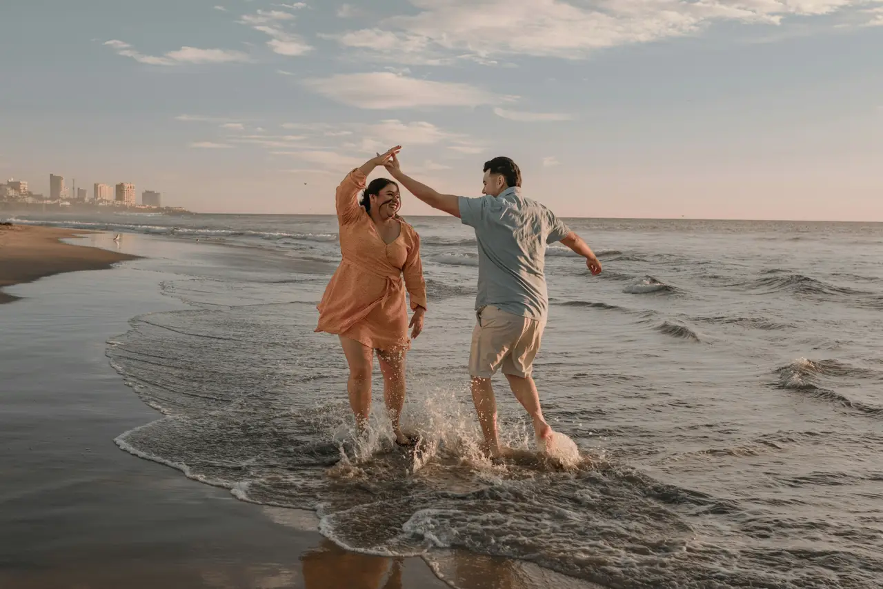 A couple laughing and playing in the shallows at the beach