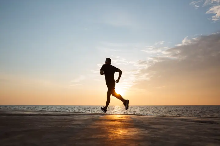 A man running along the beach at sunrise